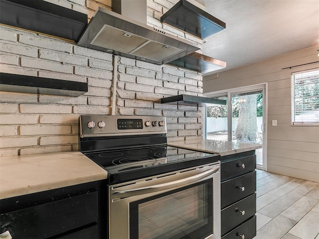 1117 Washington St, Edmond, OK 73034 - kitchen with stainless steel electric range, wall chimney range hood, open shelves, dark cabinets, and light countertops