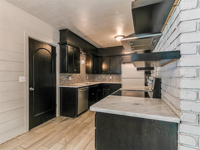1117 Washington St, Edmond, OK 73034 - kitchen with stainless steel dishwasher, wood finish floors, freestanding refrigerator, dark cabinetry, and decorative backsplash