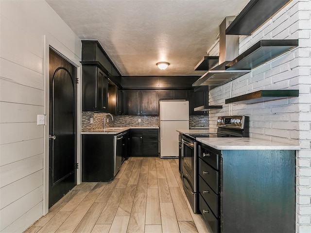 1117 Washington St, Edmond, OK 73034 - kitchen featuring appliances with stainless steel finishes, light wood-style floors, backsplash, light countertops, and dark cabinetry