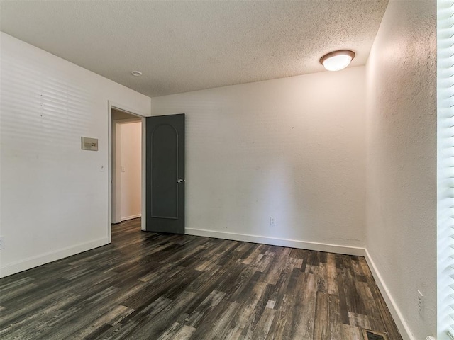 1117 Washington St, Edmond, OK 73034 - empty room featuring dark wood finished floors and a textured ceiling