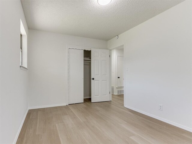7017 S Miller Ave, Oklahoma City, OK 73159 - unfurnished bedroom featuring light wood-type flooring, a textured ceiling, and a closet