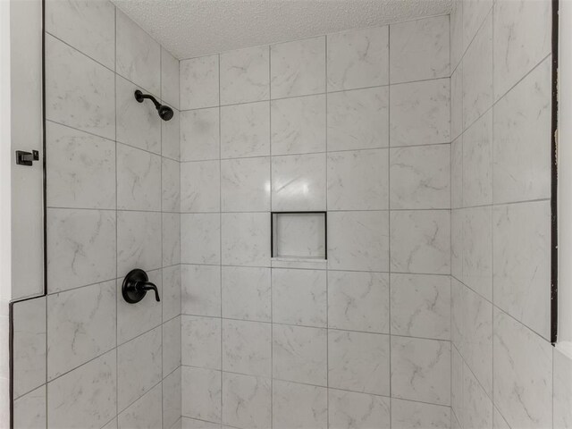 7017 S Miller Ave, Oklahoma City, OK 73159 - bathroom featuring a tile shower and a textured ceiling