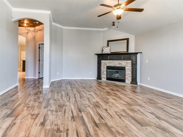 2517 NW 194th St, Edmond, OK 73012 - unfurnished living room featuring ceiling fan, wood finished floors, ornamental molding, arched walkways, and a stone fireplace