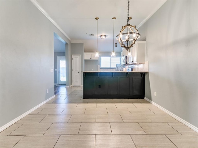 2517 NW 194th St, Edmond, OK 73012 - kitchen with a peninsula, stainless steel microwave, crown molding, white cabinets, and a chandelier