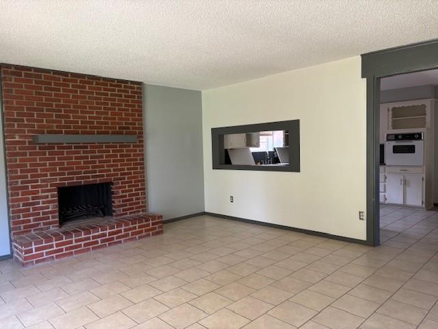 5720 Rushing Rd, Oklahoma City, OK 73132 - unfurnished living room with a textured ceiling and a brick fireplace