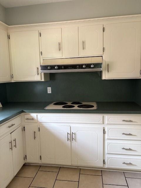 5720 Rushing Rd, Oklahoma City, OK 73132 - kitchen featuring white electric cooktop, exhaust hood, light tile patterned floors, dark countertops, and white cabinets