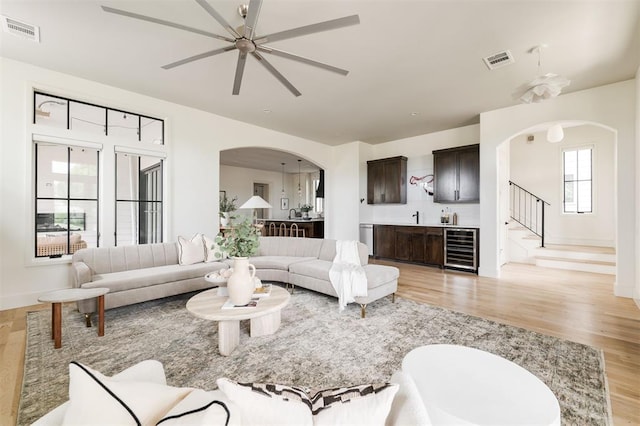 1700 Runway Blvd, Oklahoma City, OK 73108 - living room featuring beverage cooler, arched walkways, ceiling fan, bar area, and light wood-type flooring
