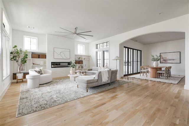 1700 Runway Blvd, Oklahoma City, OK 73108 - living room featuring arched walkways, light wood-style flooring, a ceiling fan, and a large fireplace