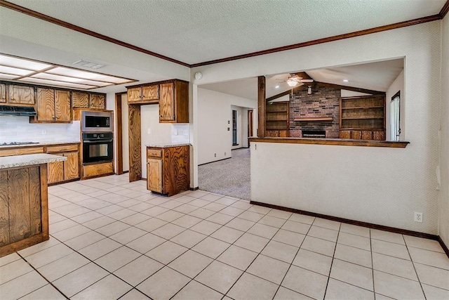1405 Creston Way, Edmond, OK 73012 - kitchen with oven, stainless steel microwave, brown cabinets, under cabinet range hood, and open floor plan