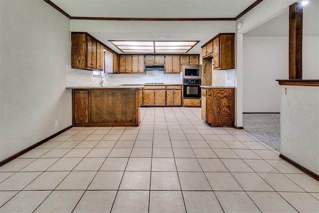 1405 Creston Way, Edmond, OK 73012 - kitchen with black oven, stainless steel microwave, brown cabinetry, a peninsula, and light countertops
