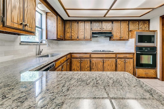 1405 Creston Way, Edmond, OK 73012 - kitchen with stainless steel appliances, under cabinet range hood, brown cabinets, and light stone countertops