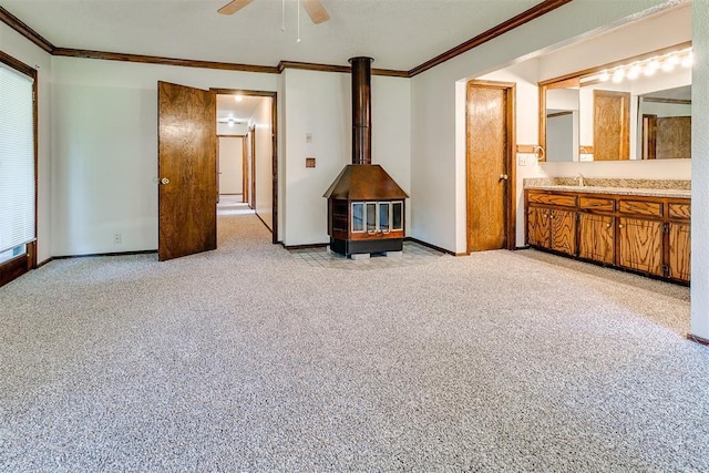 1405 Creston Way, Edmond, OK 73012 - unfurnished living room featuring ornamental molding, a ceiling fan, a wood stove, and light carpet