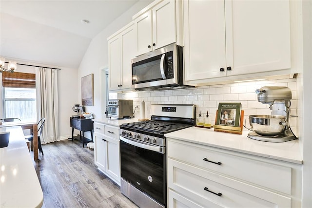 16336 Coldfire Rd, Oklahoma City, OK 73170 - kitchen featuring appliances with stainless steel finishes, lofted ceiling, backsplash, light countertops, and light wood-style flooring