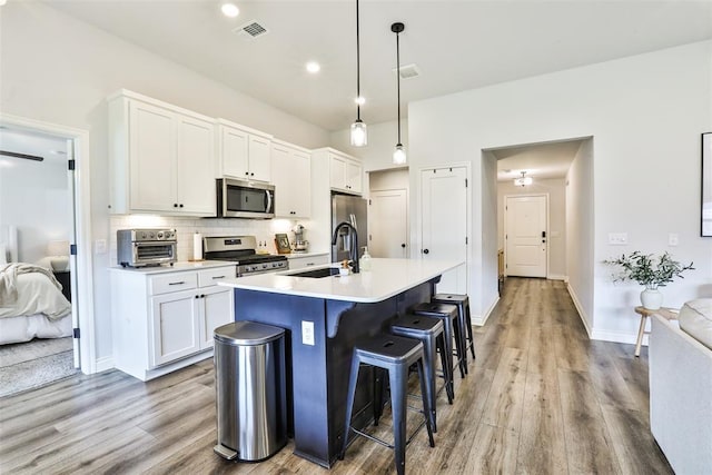 16336 Coldfire Rd, Oklahoma City, OK 73170 - kitchen with stainless steel appliances, wood finished floors, decorative backsplash, white cabinetry, and recessed lighting