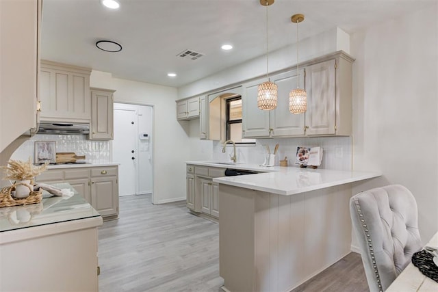 2617 NW 58th St, Oklahoma City, OK 73112 - kitchen featuring exhaust hood, a peninsula, backsplash, light wood-style flooring, and light countertops