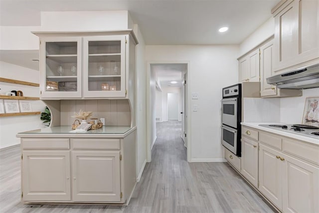 2617 NW 58th St, Oklahoma City, OK 73112 - kitchen featuring stainless steel double oven, white electric stovetop, light countertops, tasteful backsplash, and light wood-type flooring