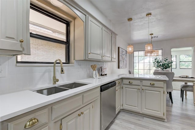 2617 NW 58th St, Oklahoma City, OK 73112 - kitchen featuring stainless steel dishwasher, a peninsula, light countertops, and decorative backsplash
