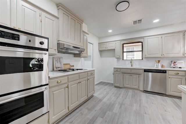 2617 NW 58th St, Oklahoma City, OK 73112 - kitchen featuring appliances with stainless steel finishes, under cabinet range hood, backsplash, light countertops, and recessed lighting
