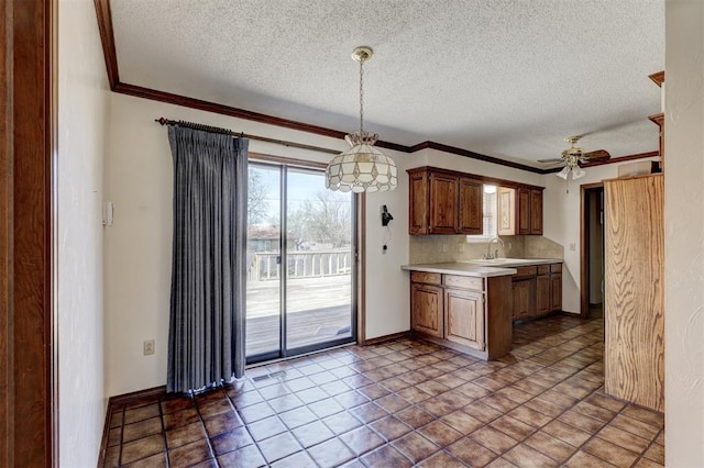 302 Tanglewood Dr, Yukon, OK 73099 - kitchen with light countertops, a textured ceiling, a ceiling fan, crown molding, and pendant lighting