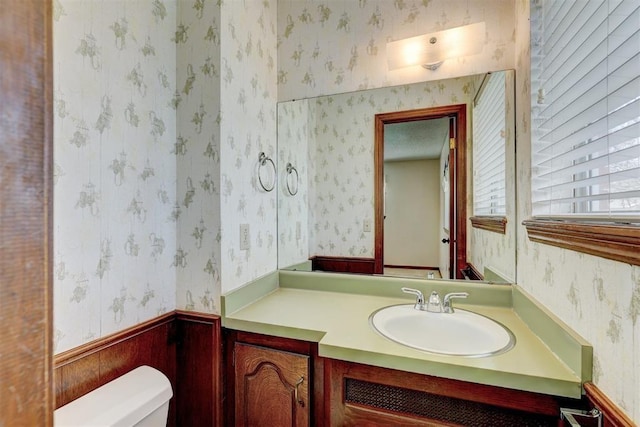 302 Tanglewood Dr, Yukon, OK 73099 - bathroom with wallpapered walls, vanity, and a wainscoted wall