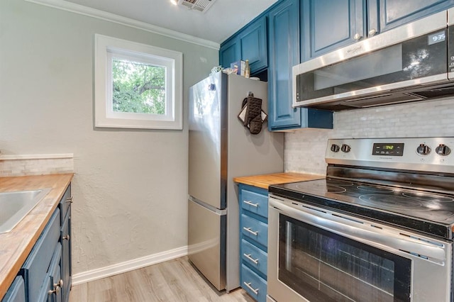 707 NE 18th St, Oklahoma City, OK 73105 - kitchen with appliances with stainless steel finishes, blue cabinetry, butcher block counters, backsplash, and light wood-style floors
