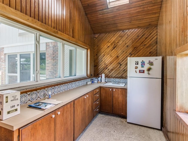 9 Country Club Rd, Shawnee, OK 74801 - kitchen with freestanding refrigerator, wood walls, light countertops, brown cabinetry, and wood ceiling