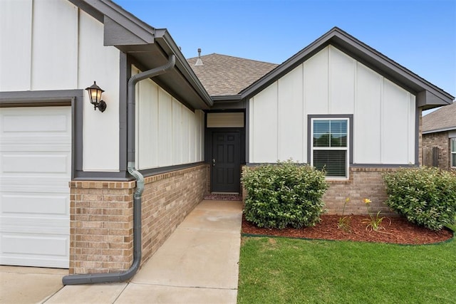 14308 Peach Tree Dr, Yukon, OK 73099 - doorway to property with brick siding, a garage, roof with shingles, and board and batten siding