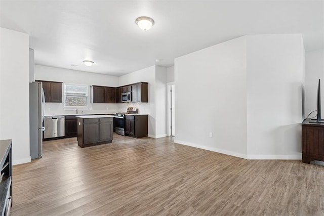 14308 Peach Tree Dr, Yukon, OK 73099 - kitchen featuring appliances with stainless steel finishes, light wood-type flooring, dark brown cabinetry, and a center island