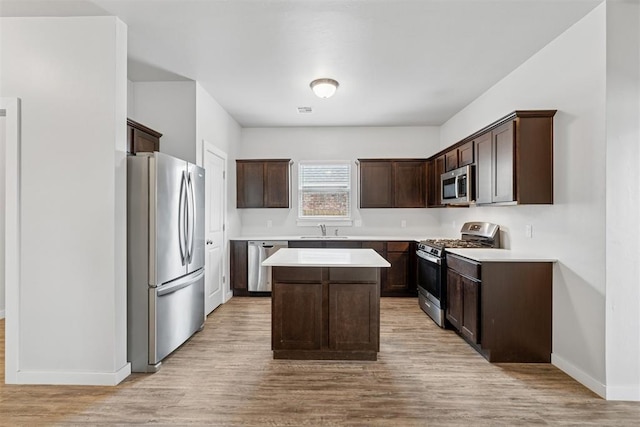 14308 Peach Tree Dr, Yukon, OK 73099 - kitchen with stainless steel appliances, a center island, dark brown cabinets, light wood-style floors, and light countertops