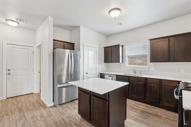 14308 Peach Tree Dr, Yukon, OK 73099 - kitchen with stainless steel appliances, light wood-style flooring, dark brown cabinetry, light countertops, and a center island