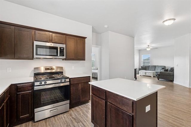 14308 Peach Tree Dr, Yukon, OK 73099 - kitchen featuring appliances with stainless steel finishes, light wood-style flooring, a ceiling fan, light countertops, and dark brown cabinetry