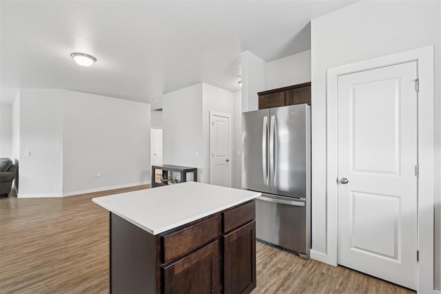 14308 Peach Tree Dr, Yukon, OK 73099 - kitchen featuring freestanding refrigerator, light wood-style floors, dark brown cabinetry, light countertops, and a center island