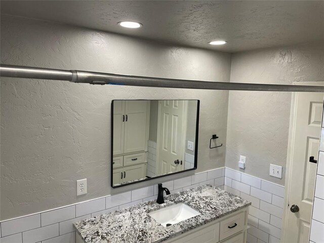 3017 Kelsey Dr, Edmond, OK 73013 - bathroom with vanity, a textured wall, tile walls, wainscoting, and recessed lighting