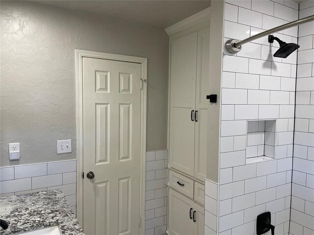 3017 Kelsey Dr, Edmond, OK 73013 - full bath featuring a tile shower, tile walls, vanity, and a textured wall