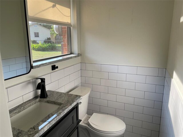 3017 Kelsey Dr, Edmond, OK 73013 - bathroom featuring tile walls, vanity, toilet, and wainscoting
