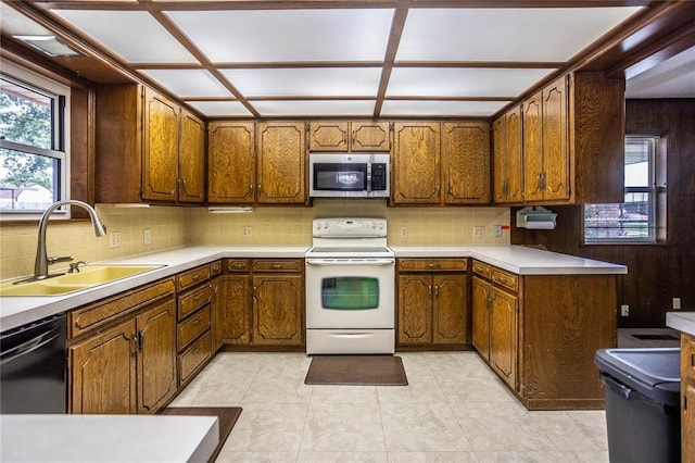 801 N Hunt St, Hydro, OK 73048 - kitchen featuring stainless steel microwave, white electric stove, black dishwasher, backsplash, and brown cabinetry