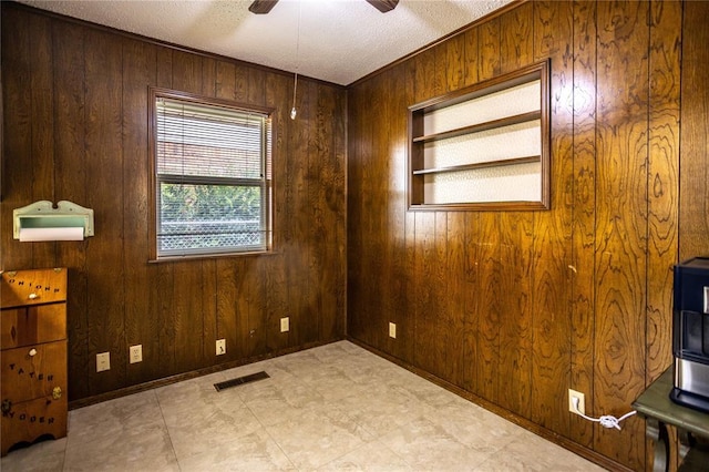 801 N Hunt St, Hydro, OK 73048 - empty room featuring wooden walls, a ceiling fan, and a textured ceiling
