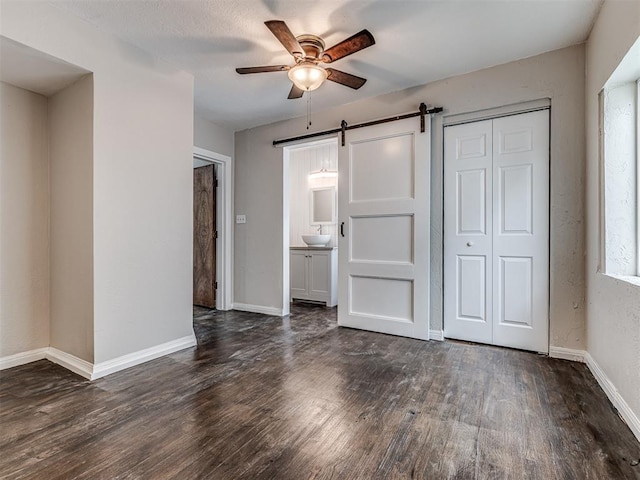 3157 NW 25th St, Oklahoma City, OK 73107 - unfurnished bedroom with a barn door, wood finished floors, a closet, and ceiling fan