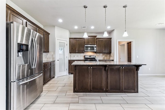 868 Phils Way, Piedmont, OK 73078 - kitchen with stainless steel appliances, tasteful backsplash, dark brown cabinetry, dark stone countertops, and a center island with sink