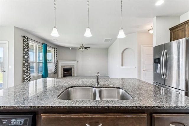 868 Phils Way, Piedmont, OK 73078 - kitchen with stainless steel fridge with ice dispenser, ceiling fan, dark brown cabinets, a tiled fireplace, and dark stone counters