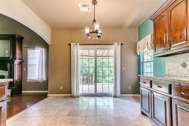 3393 Creek View Ct, Newcastle, OK 73065 - kitchen with baseboards, stone tile flooring, decorative light fixtures, and arched walkways