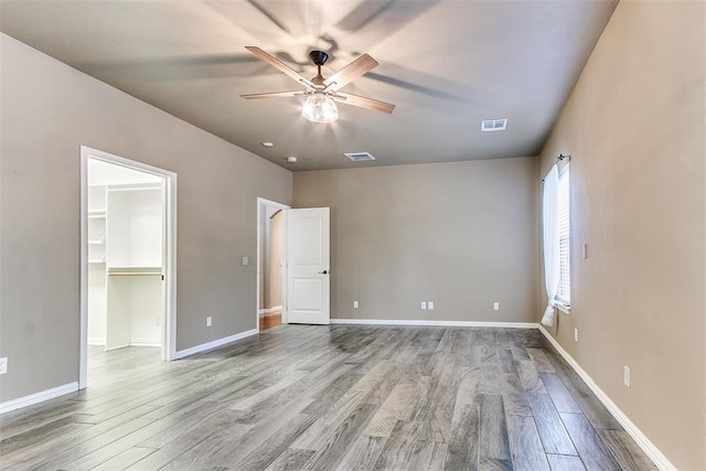 3393 Creek View Ct, Newcastle, OK 73065 - unfurnished bedroom featuring wood finished floors, a walk in closet, baseboards, and a ceiling fan