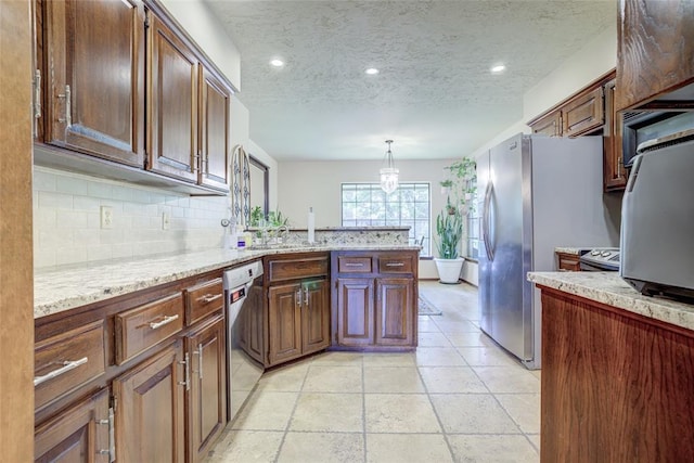 2010 Trailview Ct, Norman, OK 73072 - kitchen featuring stainless steel appliances, decorative backsplash, a peninsula, a textured ceiling, and light stone countertops