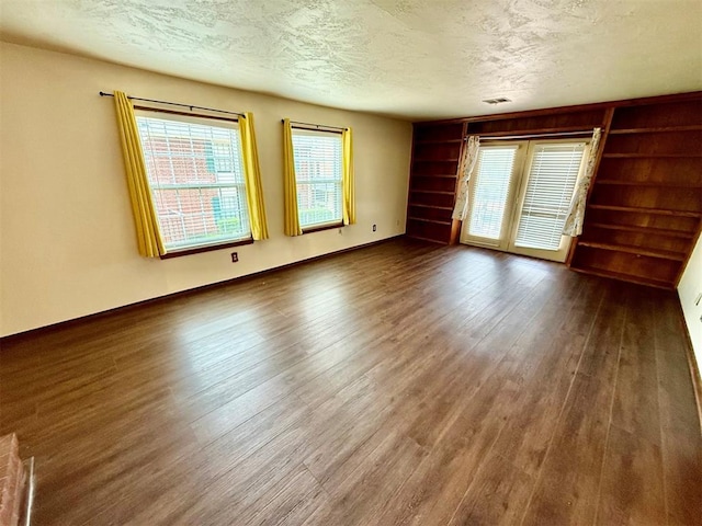 4400 Hemingway Dr Unit 263, Oklahoma City, OK 73118 - empty room featuring wood finished floors, a textured ceiling, built in shelves, and baseboards