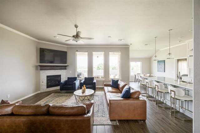 10800 NW 5th St, Yukon, OK 73099 - living room with dark wood-style floors, a stone fireplace, ceiling fan, and ornamental molding