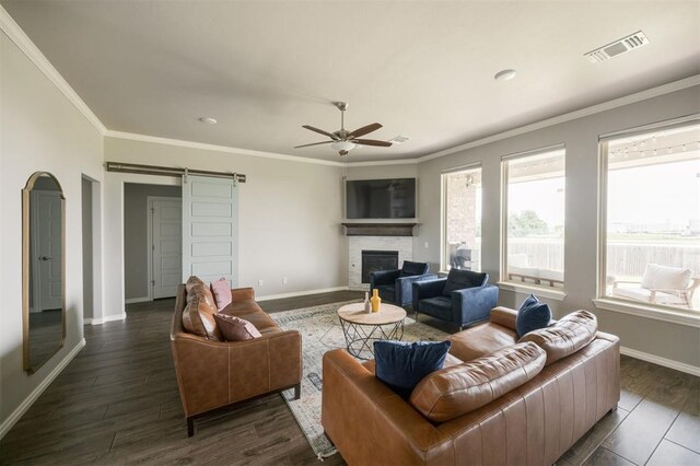10800 NW 5th St, Yukon, OK 73099 - living room with a barn door, a ceiling fan, dark wood finished floors, a glass covered fireplace, and crown molding