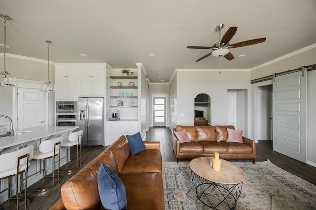 10800 NW 5th St, Yukon, OK 73099 - living room with a barn door, ceiling fan, dark wood finished floors, and crown molding