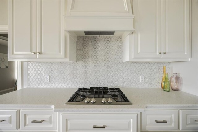 10800 NW 5th St, Yukon, OK 73099 - kitchen with stainless steel gas stovetop, custom exhaust hood, backsplash, white cabinets, and light stone counters