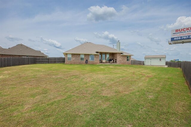 10800 NW 5th St, Yukon, OK 73099 - back of house featuring a fenced backyard, brick siding, and an outdoor structure