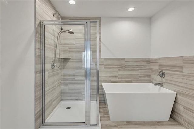 14500 Gravity Falls Ln, Oklahoma City, OK 73142 - full bathroom with tile walls, a freestanding bath, a shower stall, recessed lighting, and a wainscoted wall